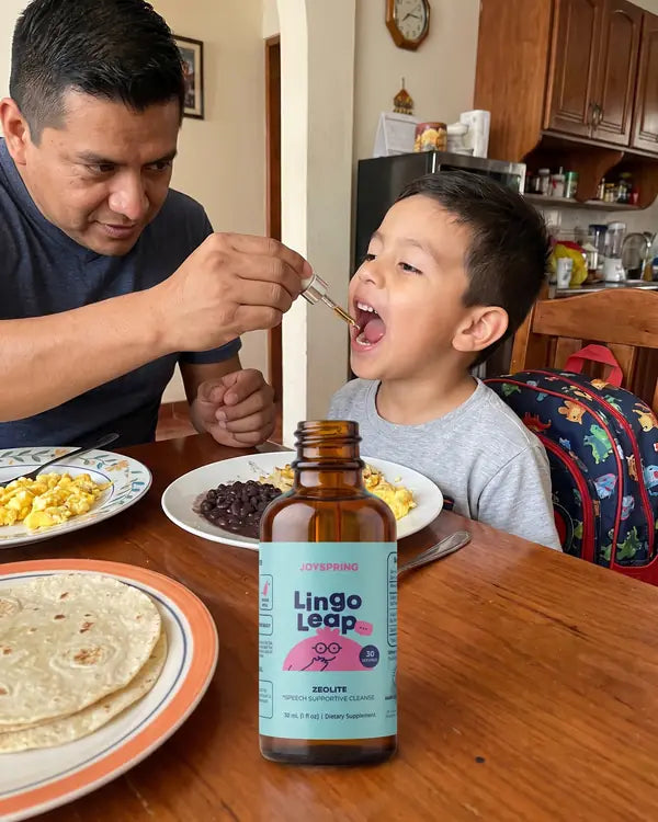 Papá dando un gotero de Lingo Leap a su hijo en el desayuno